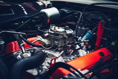 Close-up of a vehicle engine with carburetor and red valve covers