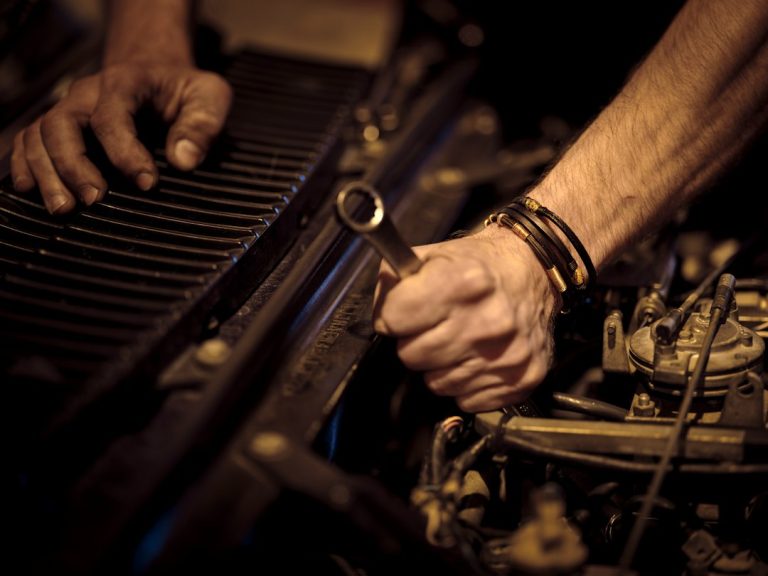Mechanic working on a vehicle engine with a wrench