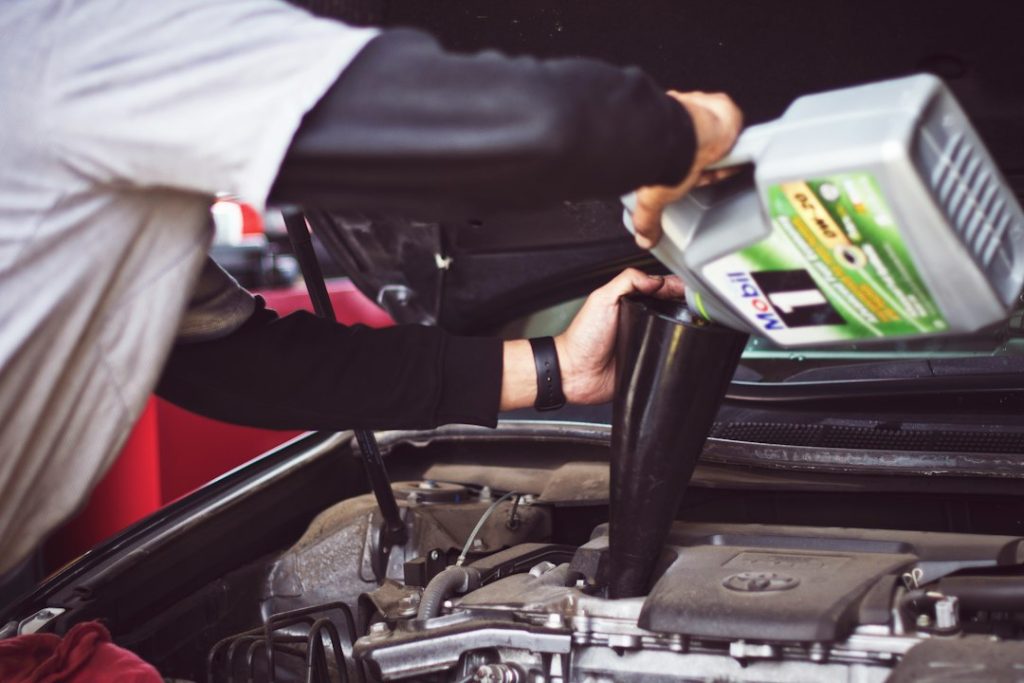 Mechanic adding motor oil through a funnel during vehicle maintenance